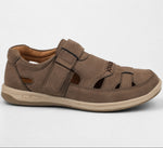 A single brown slip-on sandal with cutout details and hook-and-loop straps, shown from a side profile on a light gray background.