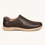A dark brown slip-on leather shoe with a textured grain upper and a light tan sole, shown from a side profile on a light cream background.